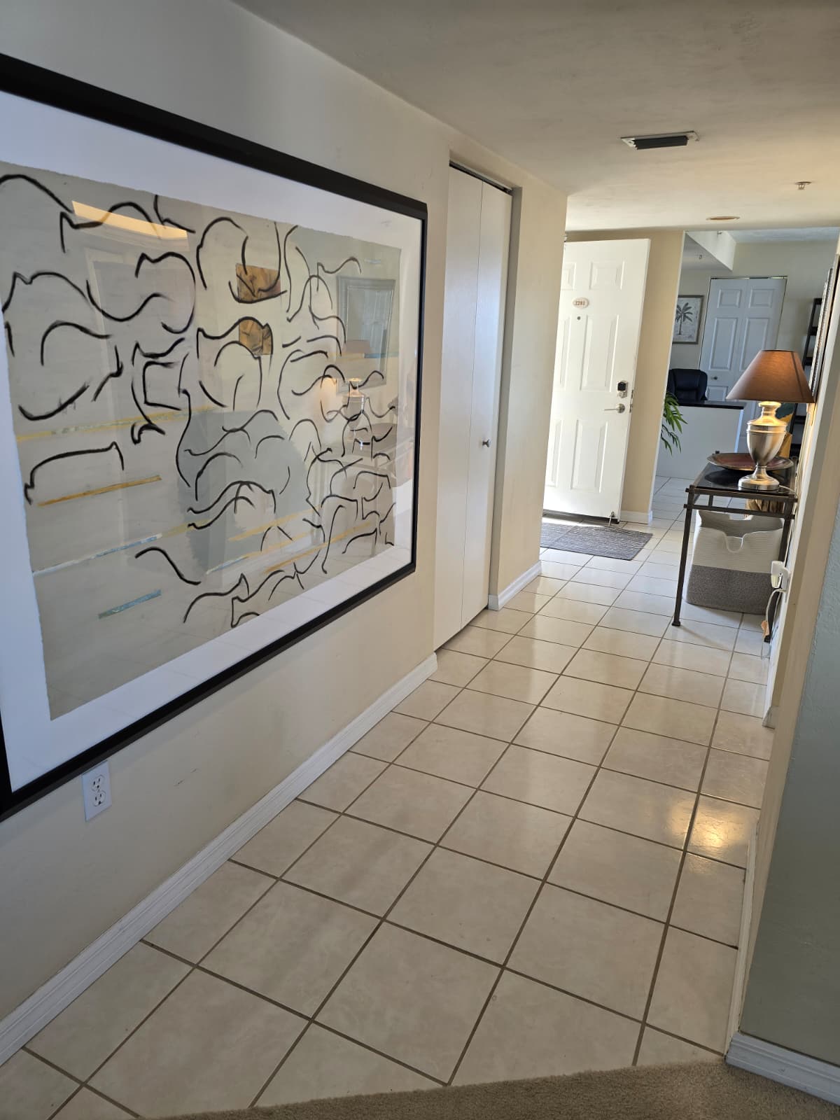 Unit entrance with pin code and main hallway with office in the background


